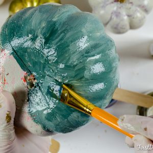 Applying blue paint to dollar store foam pumpkins