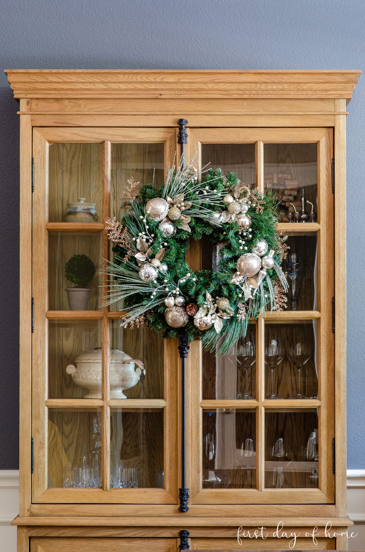 Christmas wreath with mercury glass ornaments inspired by Frontgate hanging on a cabinet in a dining room.