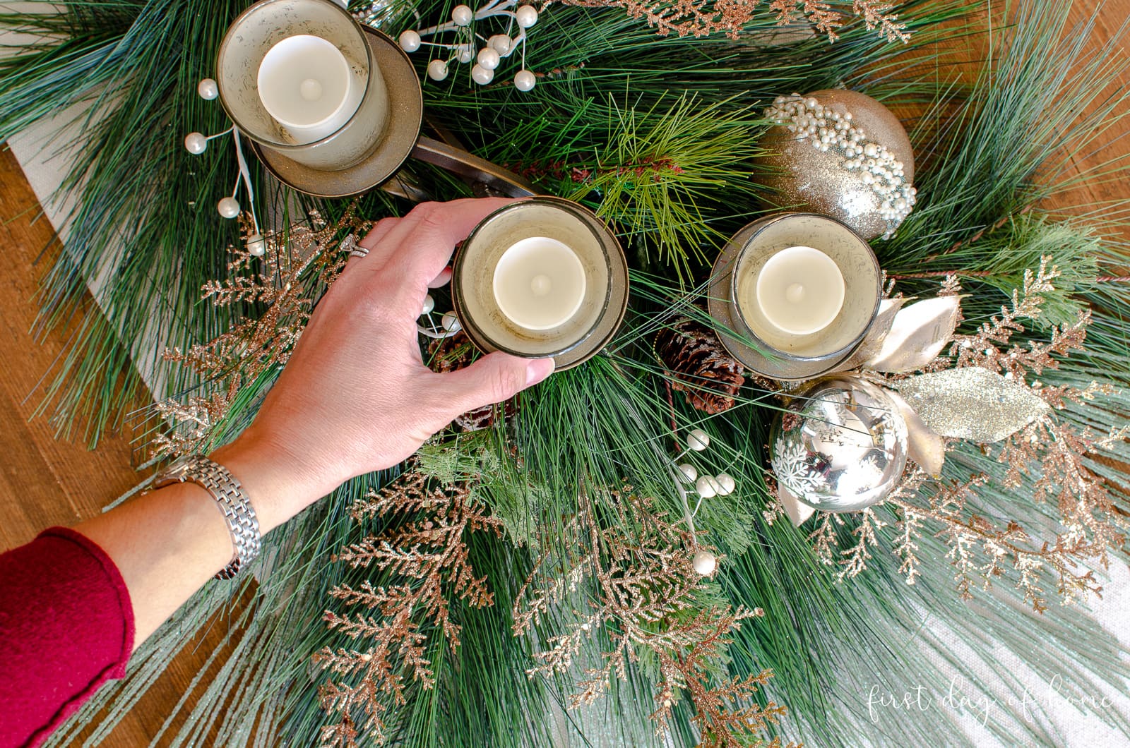Hand placing a mercury glass votive candle on candelabra for holiday table centerpiece.