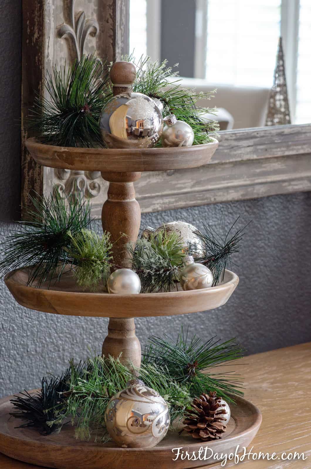 Three tiered tray decorated for Christmas with faux pine greenery and silver ornaments