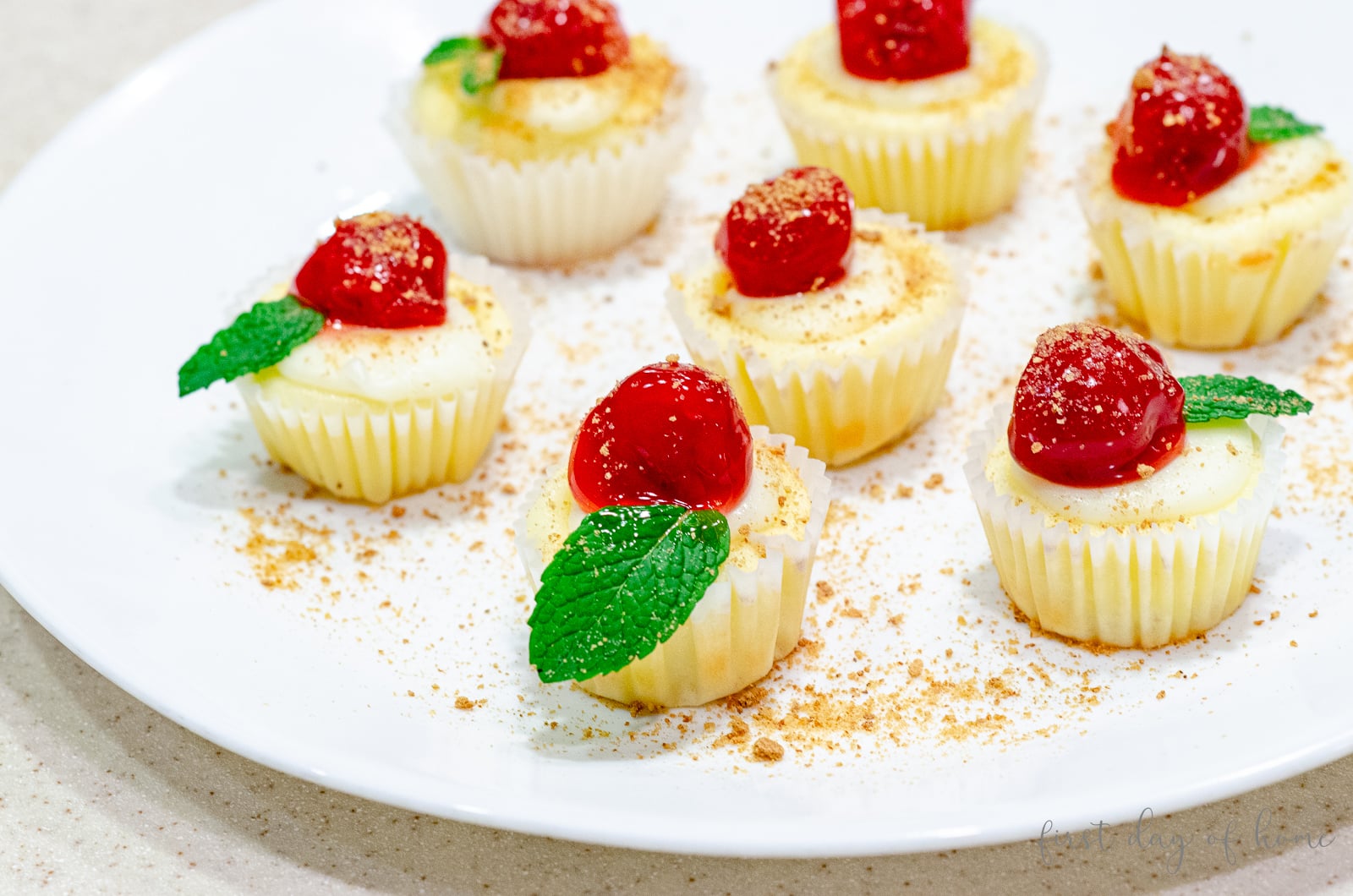 Mini cheesecakes on a plate with cherry topping and mint leaves