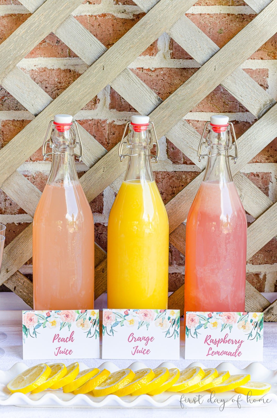 Mimosa bar juices with printable tags in front and lemon wedges to garnish