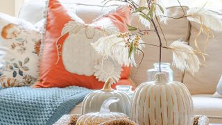 Fall coffee table decor with neutral pumpkins and wispy floral stems in woven coffee table tray