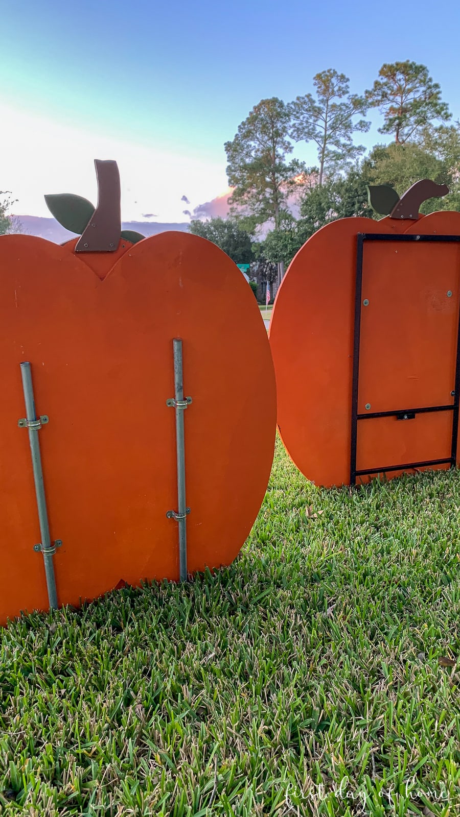 Wooden pumpkins in grass with pipe brackets and pipes attached to secure them in place