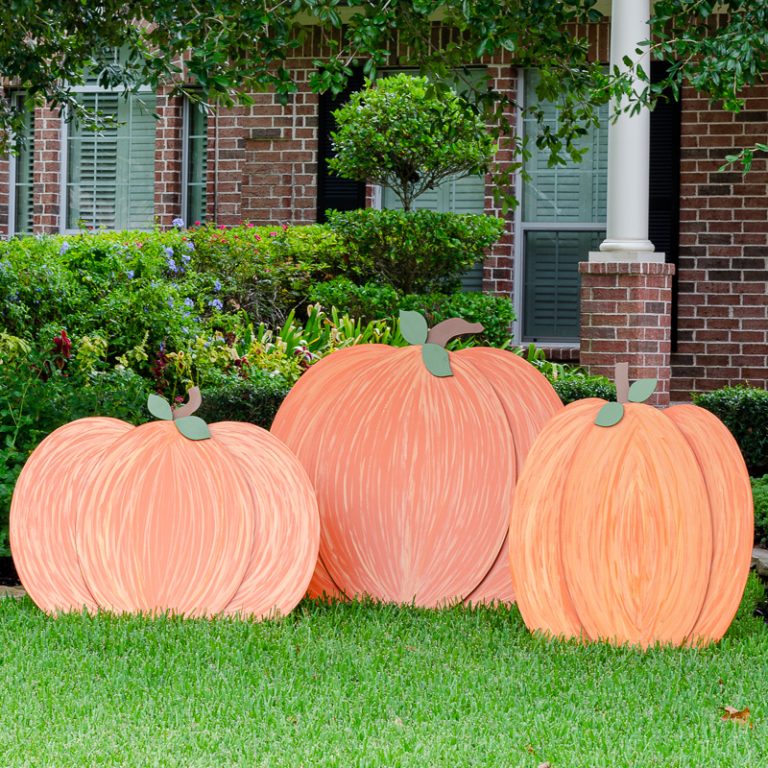 Orange painted wooden pumpkins outdoors on front lawn