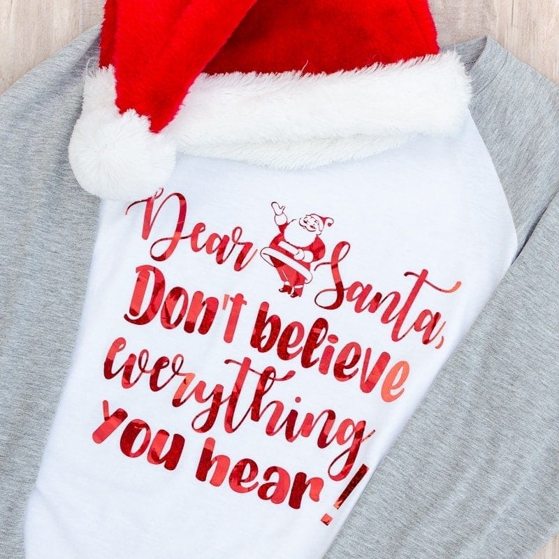 Santa SVG t-shirt that reads "Dear Santa, don't believe everything you hear!" with red letters and raglan tee with Santa hat