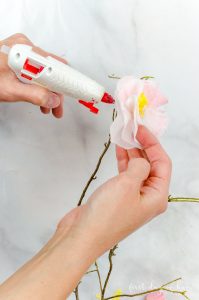 Gluing cherry blossom paper flowers onto real branches