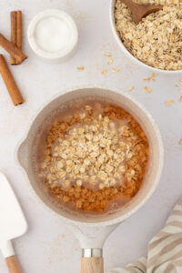 Adding oats to boiling water to make Mexican avena recipe (oatmeal with evaporated milk)