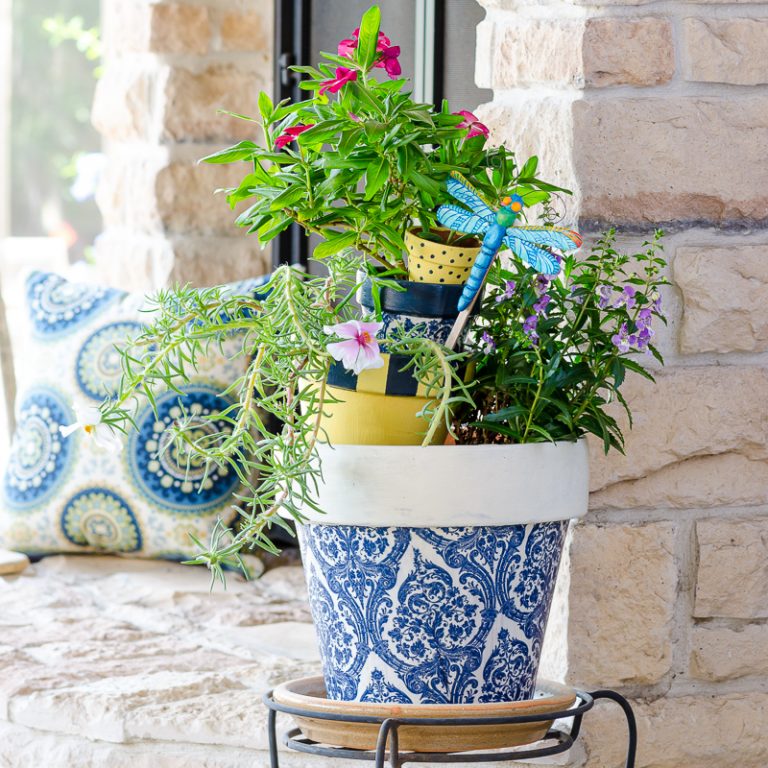 Painted terracotta pots and decoupage pots in blue, white and yellow on outdoor patio