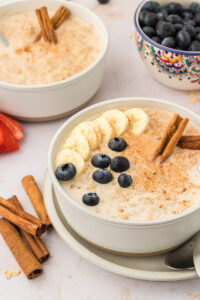 Bowls of Mexican oatmeal recipe filled with blueberries, cinnamon sticks, and bananas