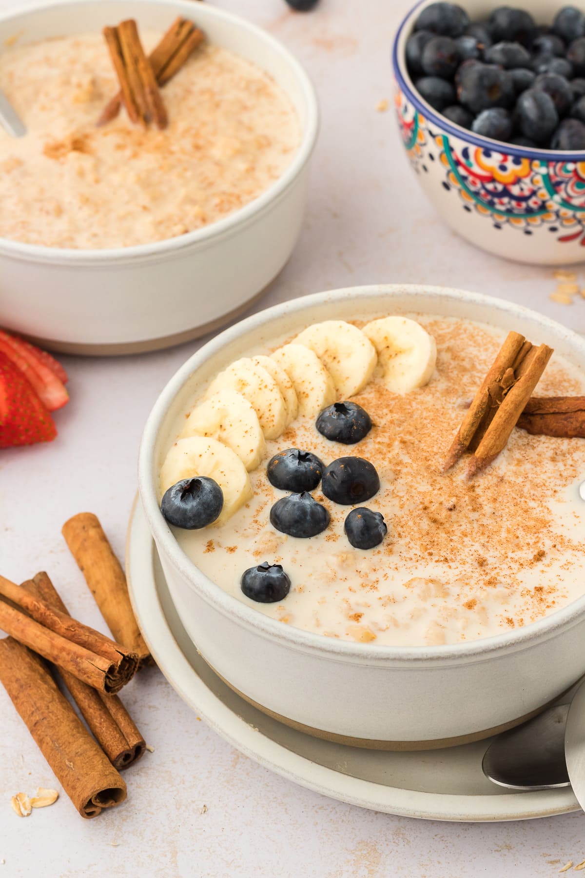 Bowls of Mexican oatmeal recipe filled with blueberries, cinnamon sticks, and bananas.
