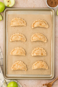 Apple empanadas with slits cut and topped with egg wash and sugar-cinnamon mixture