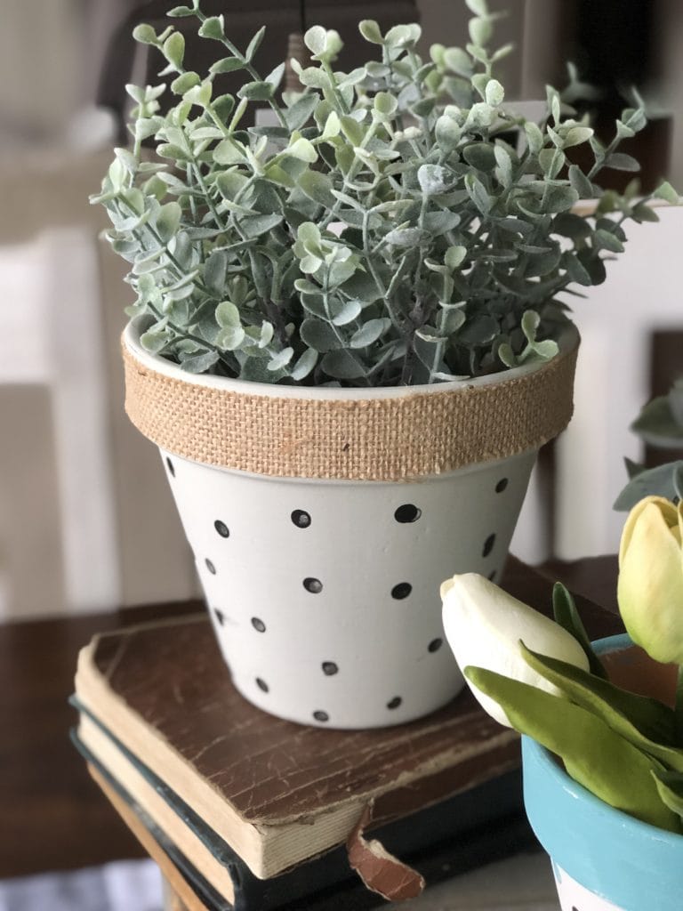 Terra cotta pot with black and white polka dots and burlap ribbon around the rim