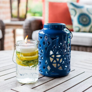 Mason jar filled with citrus, rosemary and essential oils pictured with lantern on patio table
