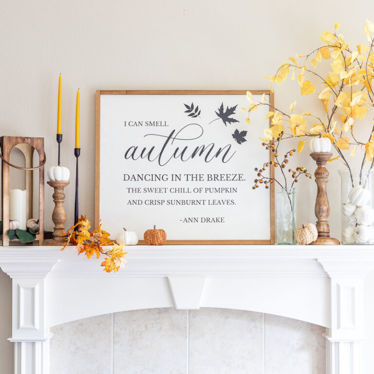 Fall mantel decor with farmhouse sign, faux aspen branches, lantern, and candlesticks with pumpkins