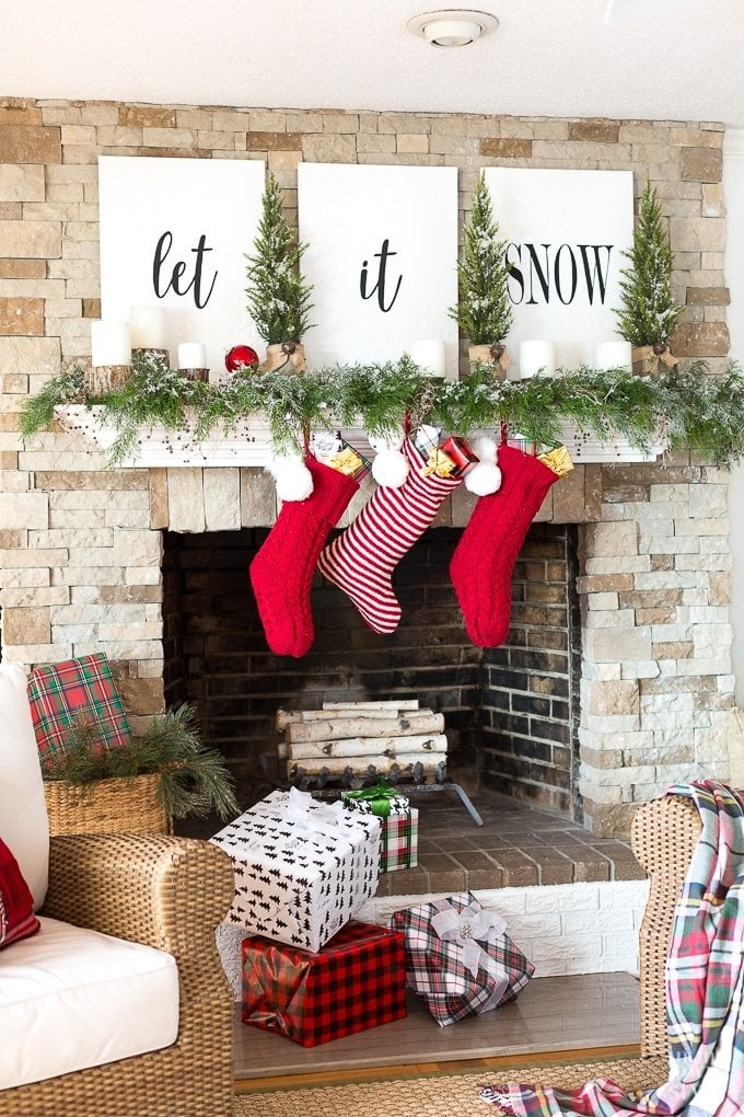 Let it Snow themed Christmas mantel decor with red and white stockings and garland