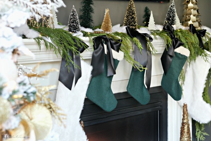 Christmas mantel with green and ivory stockings and satin bows