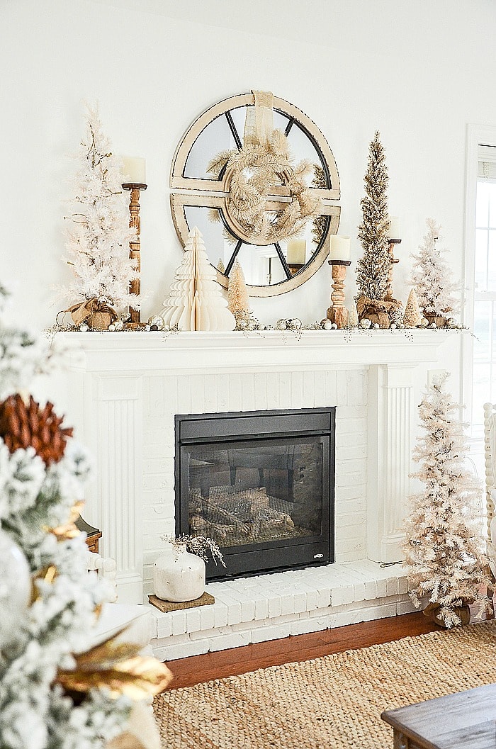Woodsy Christmas mantel with neutral candlesticks and Christmas trees with mirror in center