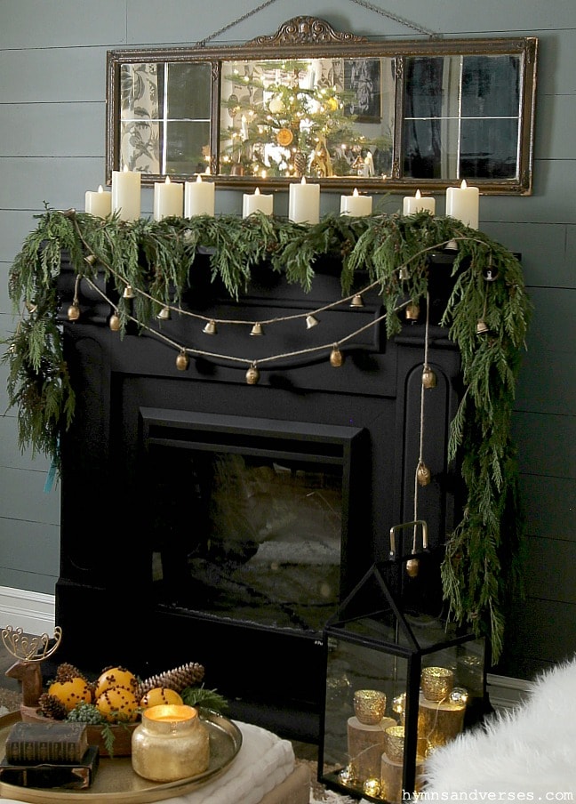 Classic Christmas mantel decor with pillar candles and cedar garland with mirror above fireplace