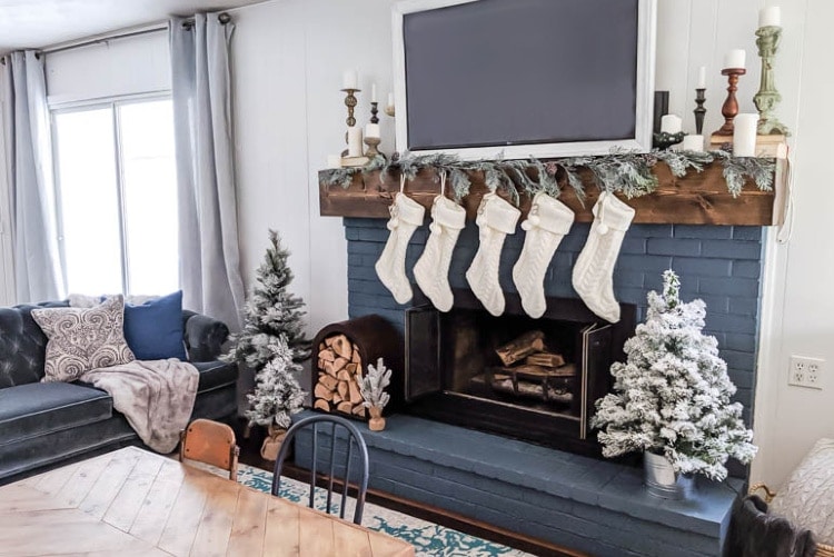 Neutral Christmas mantel decor with white stockings and wooden candleholders