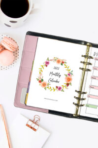 Printable calendar 2022 free printable in a planner with a cup of coffee, macarons, and notepad nearby