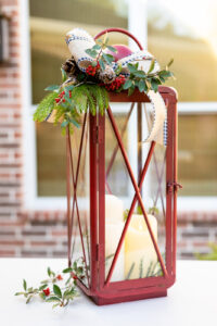 Red Christmas lantern with fresh greenery, berries, pinecones, and ribbon