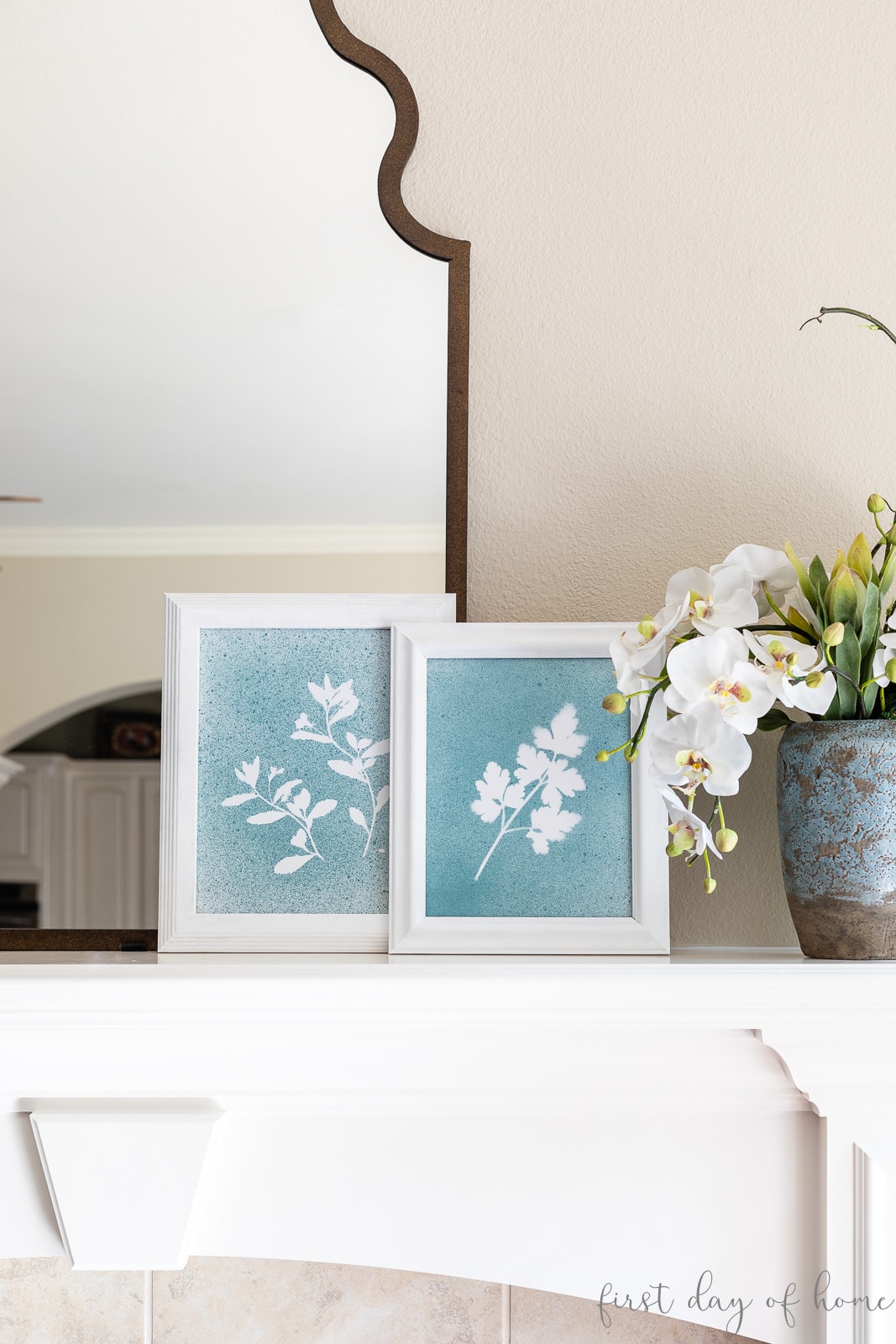 Pressed flower wall art shown in white frames next to faux floral arrangement on fireplace mantel.