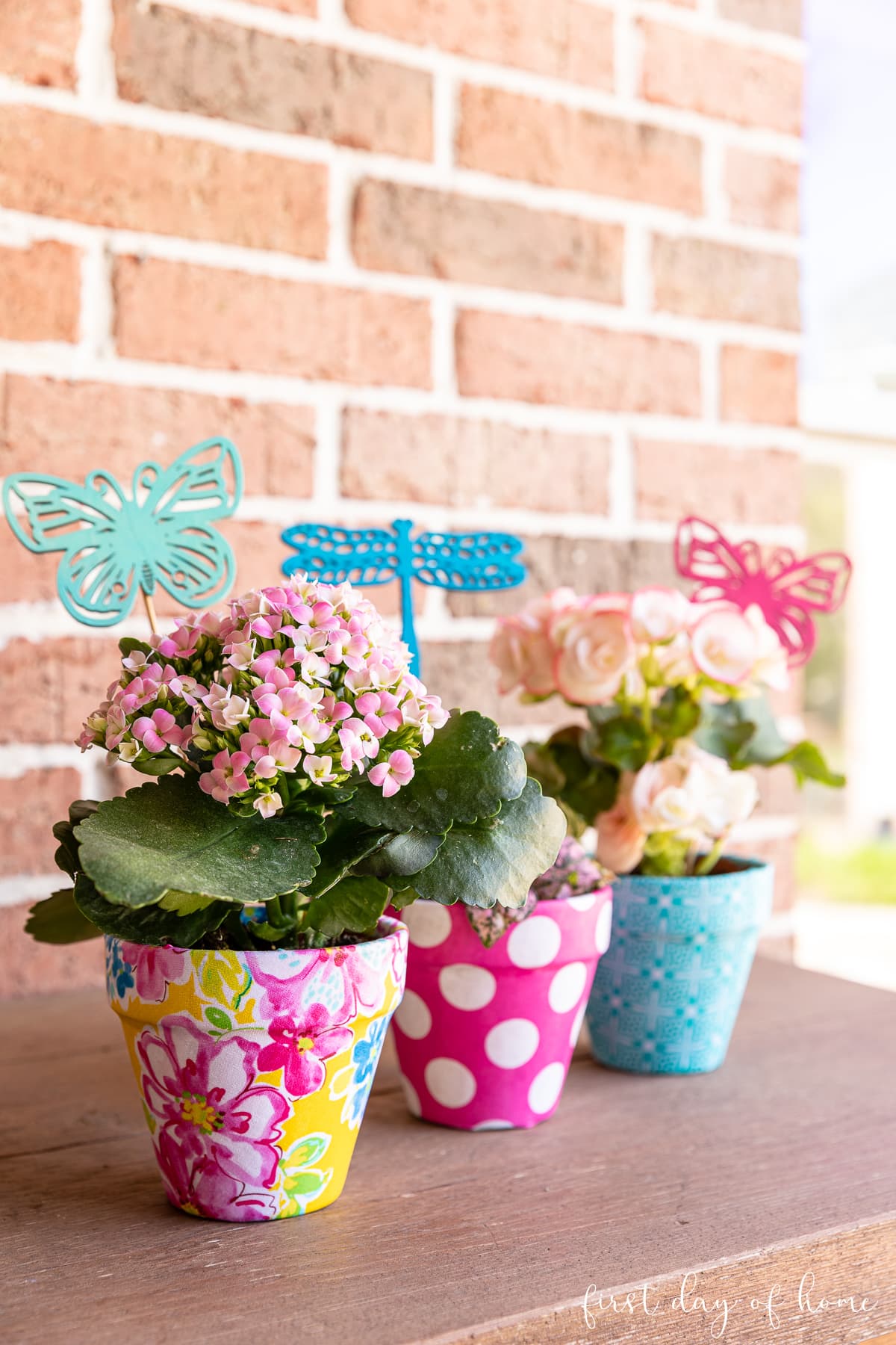 Trio of fabric covered flower pots with various spring flowers and DIY garden stakes
