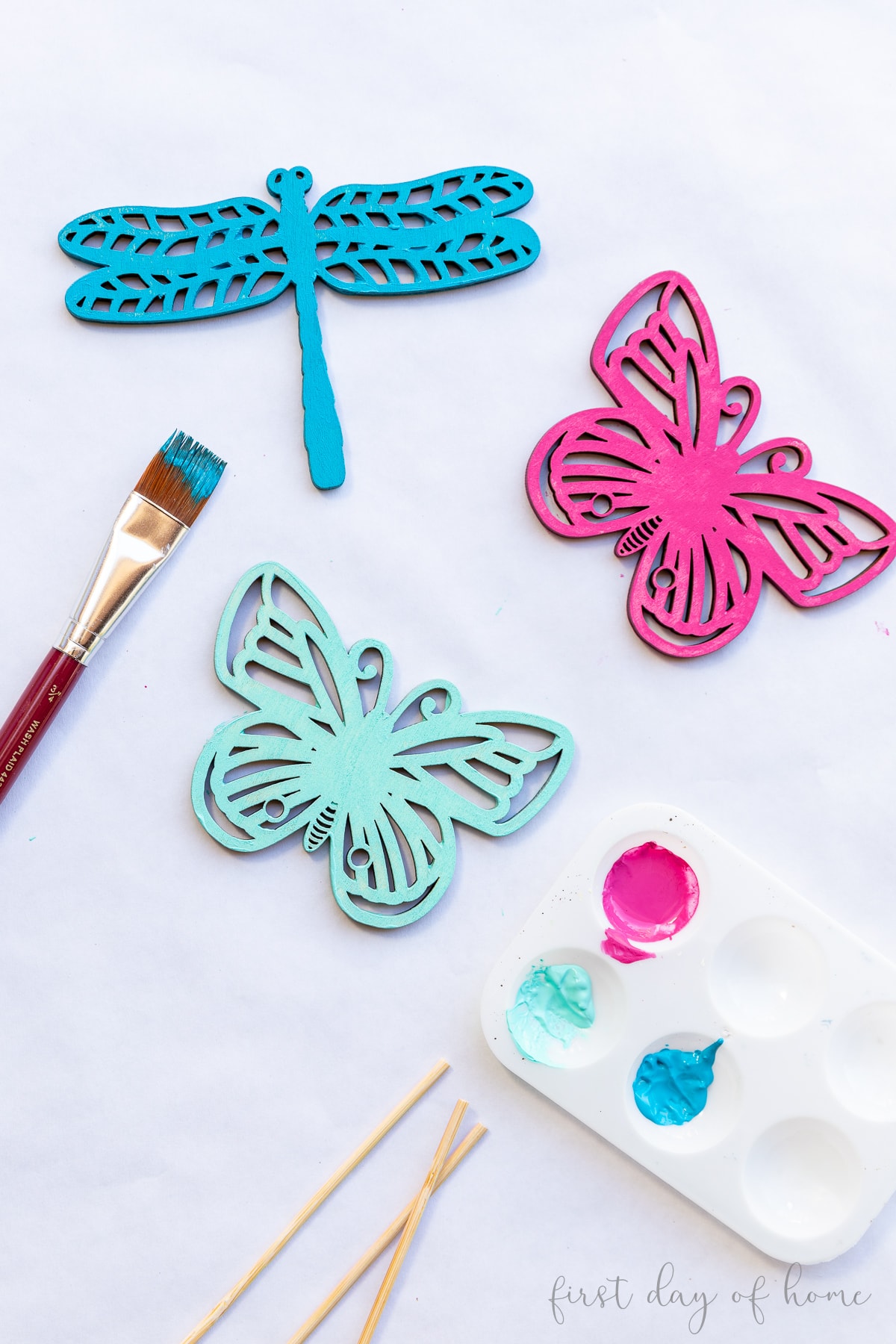 Wooden garden stakes in shapes of butterflies and dragonfly, shown with acrylic paints and paintbrush