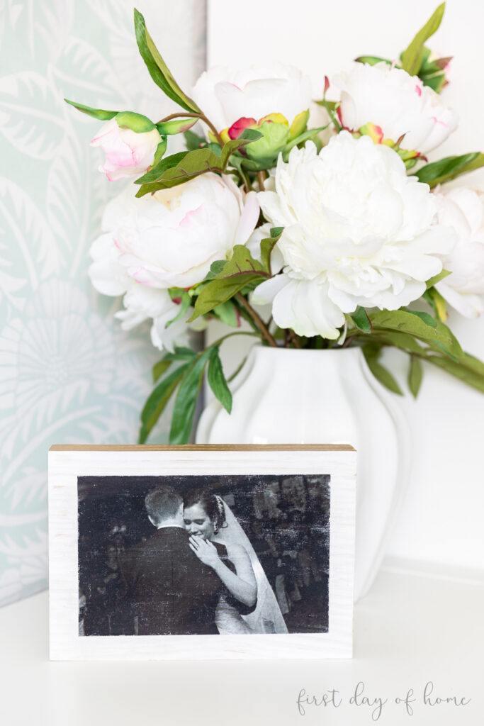 Photo transfer to wood with image of wedding couple, placed next to floral arrangement on table