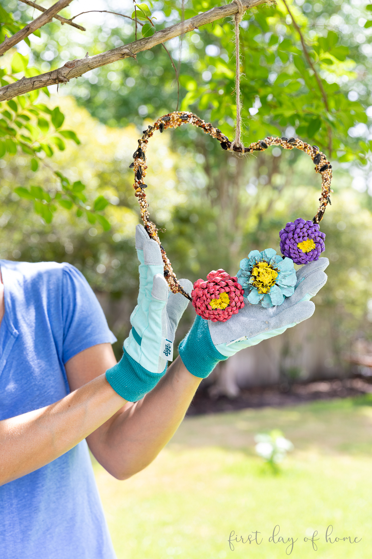 DIY bird feeder craft hanging from tree with Crissy holding the wreath from the bottom