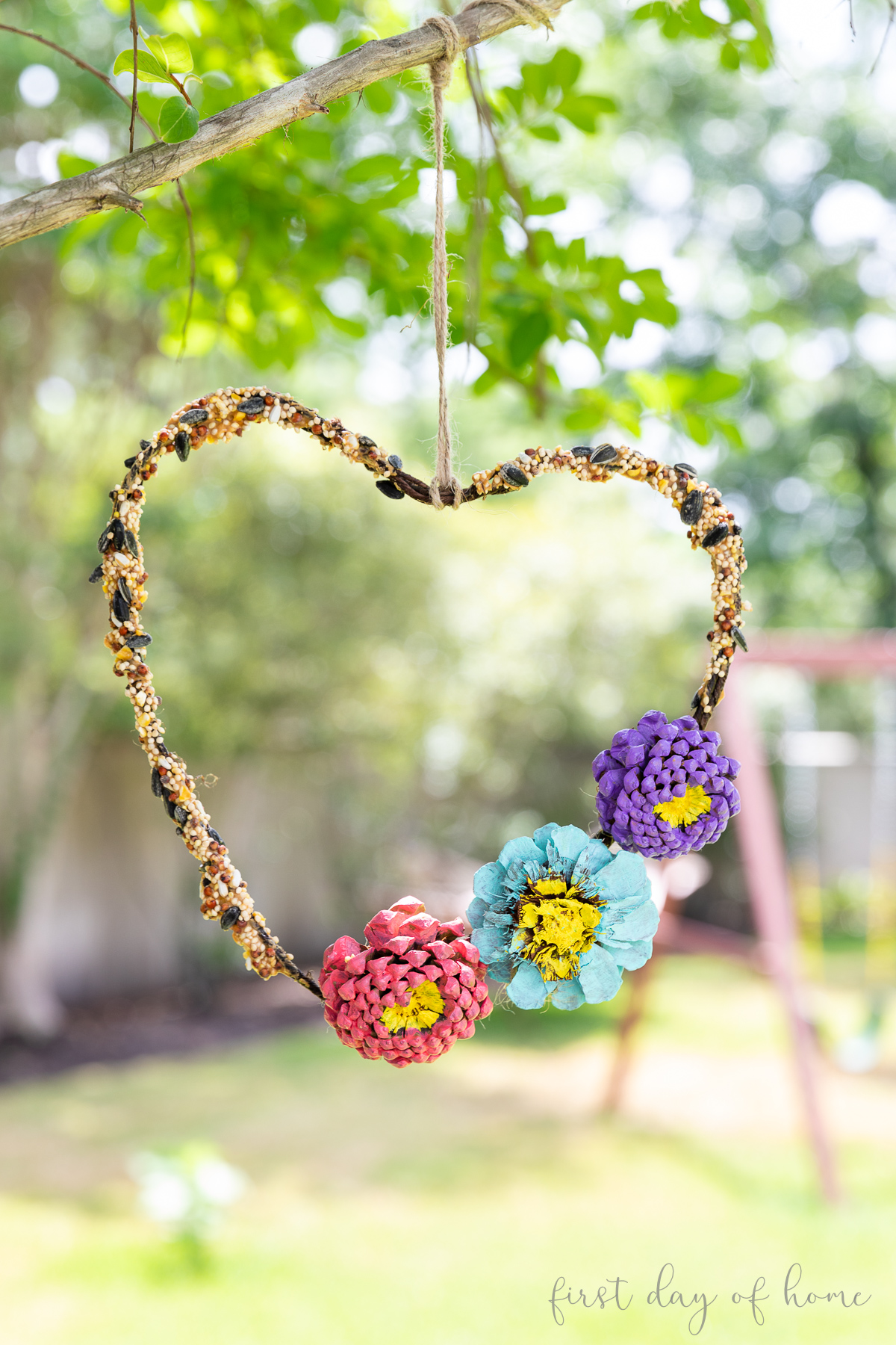 DIY bird feeder with painted pinecone accents hanging from tree branch