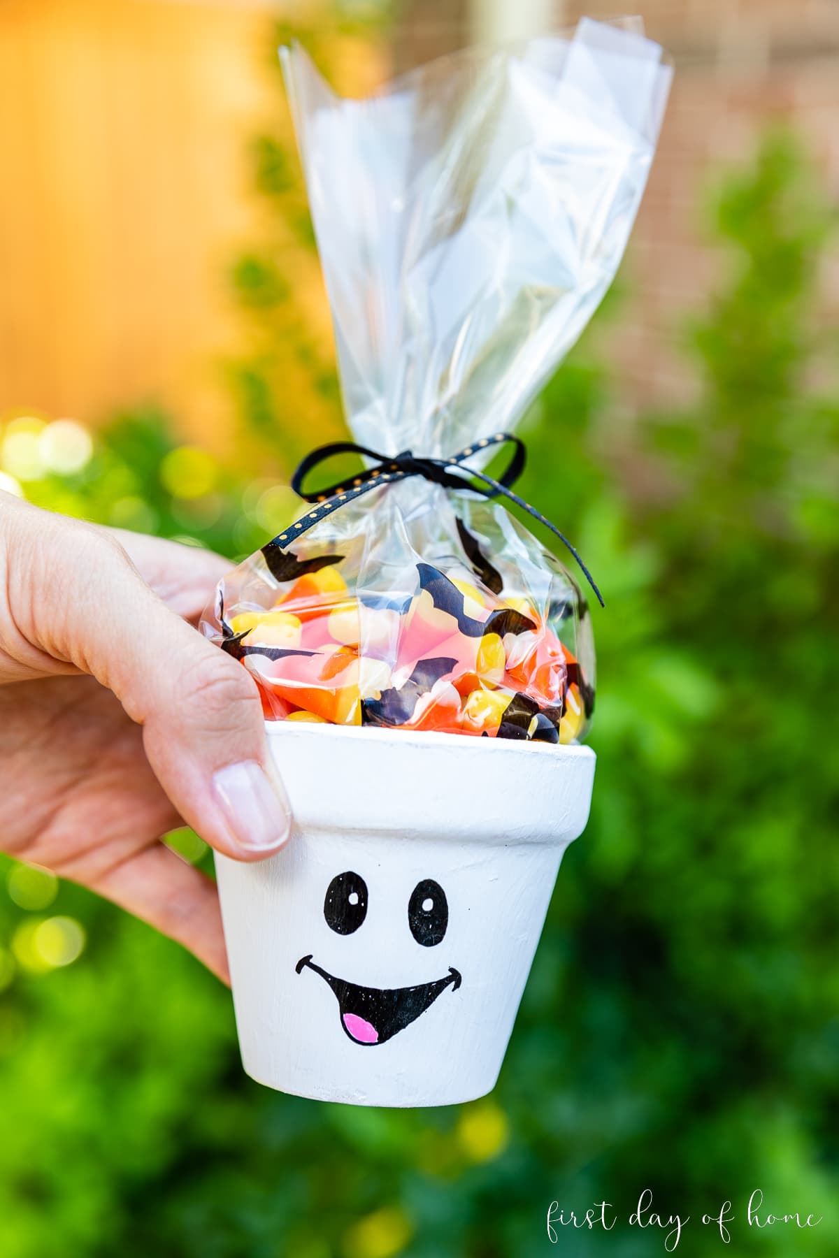Flower pot painted with a ghost face and filled with candy corns