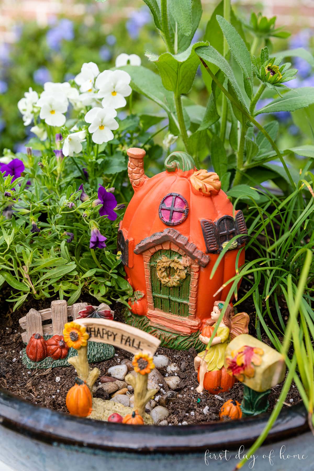 Fall fairy garden closeup view of pumpkin house and archway that reads "Happy Fall"