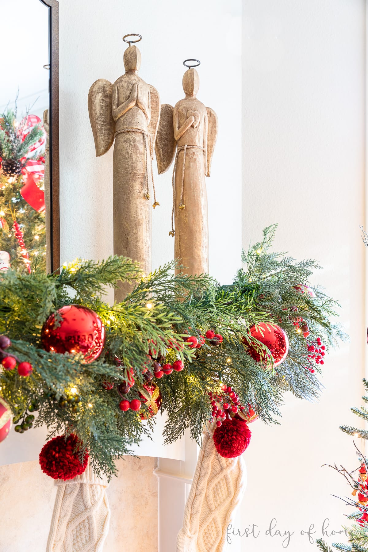 Two tall wooden angel statues sitting on a Christmas mantel 
