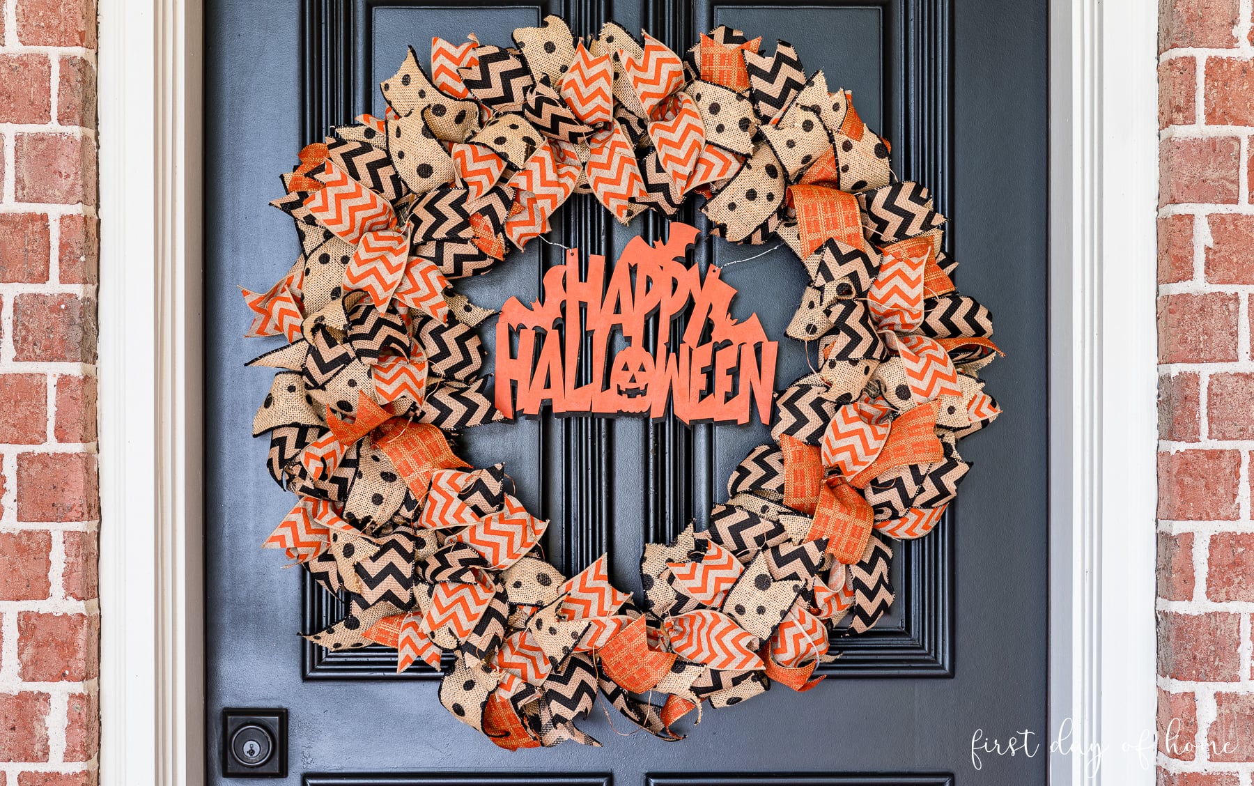 Closeup of Halloween rag wreath with burlap ribbon and wood cutout in the center.