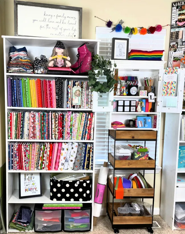 Craft room storage shelves with fabric squares organized by color