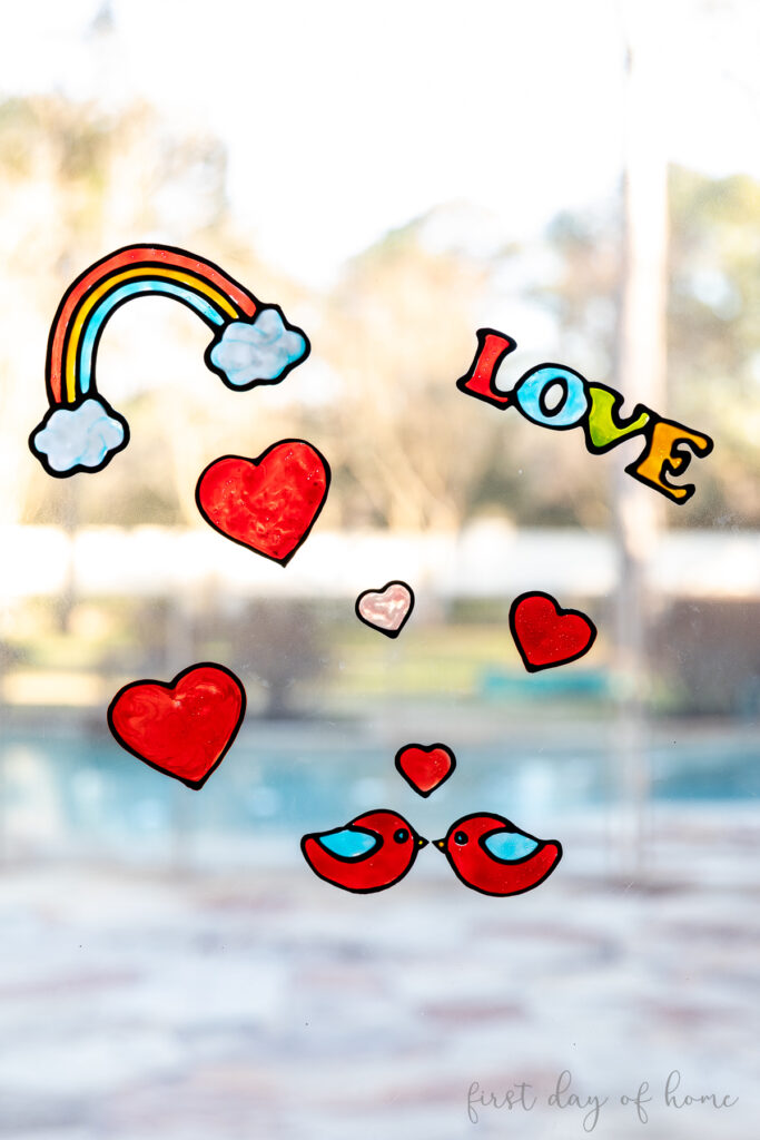 Collection of window clings on window, including a rainbow, love birds, "Love" word, and hearts