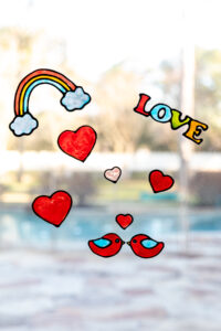 Suncatcher DIY window clings in the shapes of hearts, birds, a rainbow, and the word "Love"