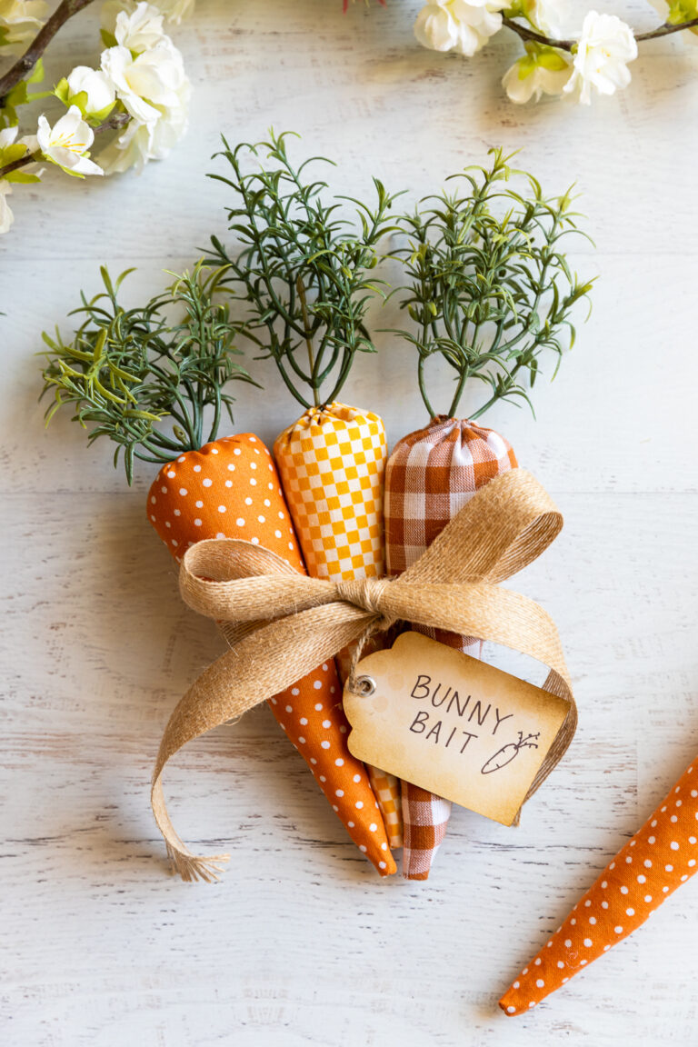 Three fabric carrots tied together with ribbon with a rustic tag that reads "bunny bait"