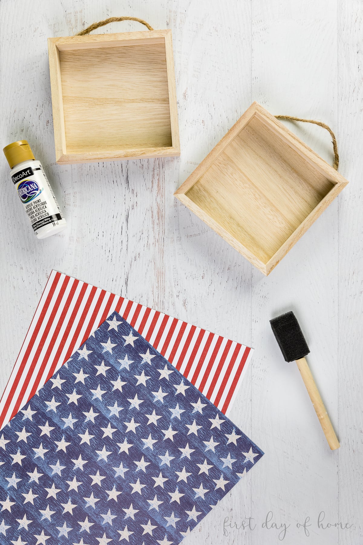 Supplies for patriotic wood signs, including wooden frames, scrapbook paper, paint brush, and acrylic paint