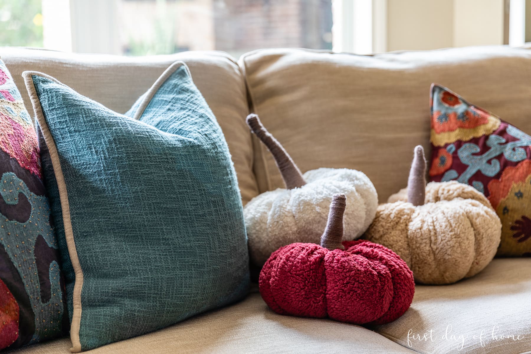 Three sherpa fabric pumpkin pillows sitting on couch.