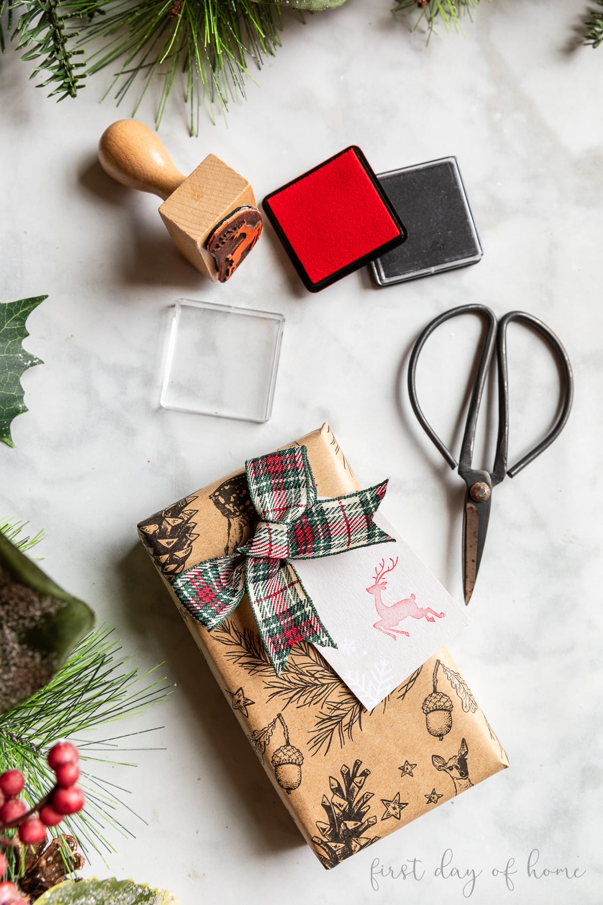 Wrapped present with ribbon and gift tag stamped with a reindeer rubber stamp, shown with ink pads and scissors