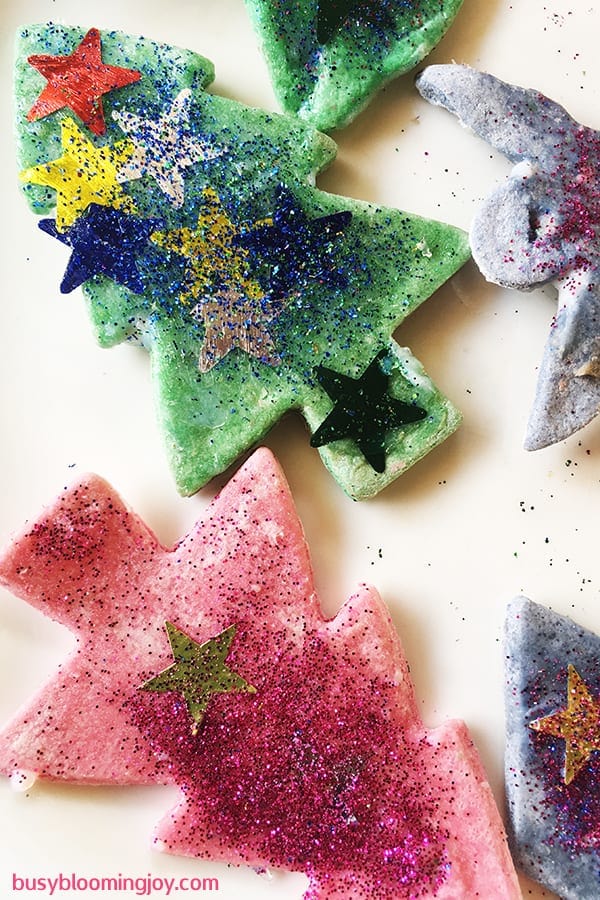 Colored salt dough Christmas tree ornaments with glitter and decorative stars.