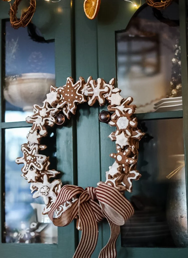 Salt dough snowflake wreath with ribbon hanging from cabinet.