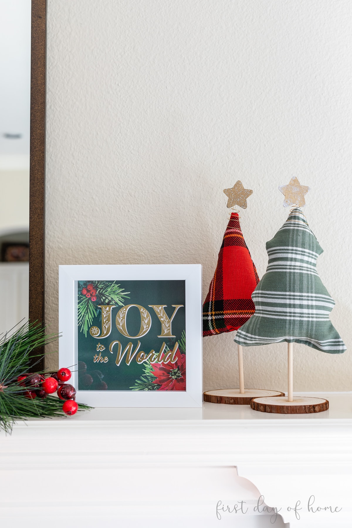Christmas shadow box that reads "Joy to the World" shown with fabric Christmas trees and faux evergreen stem and berries.