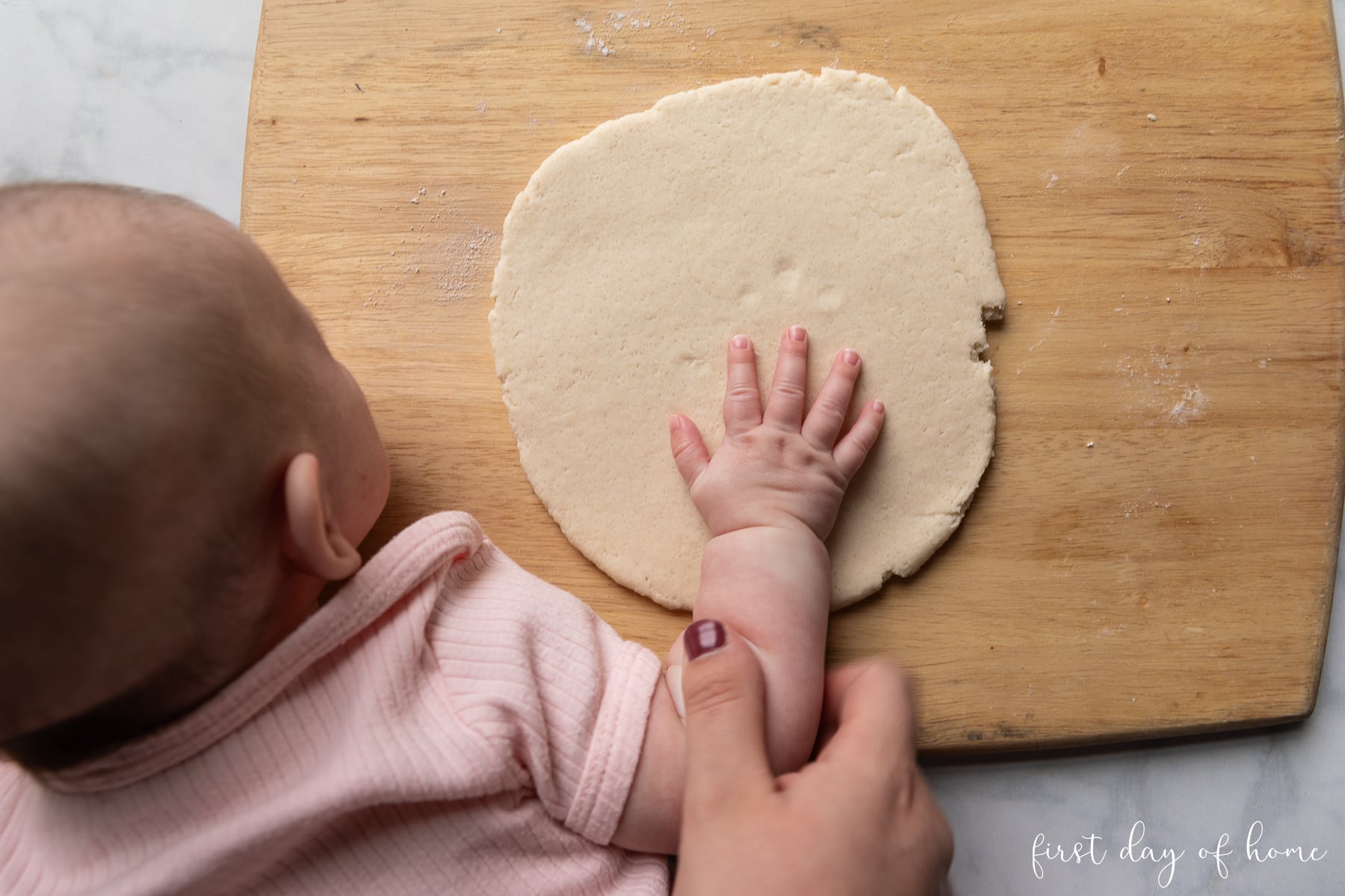 Pressing a child's handprint into salt dough to make a handprint ornament.