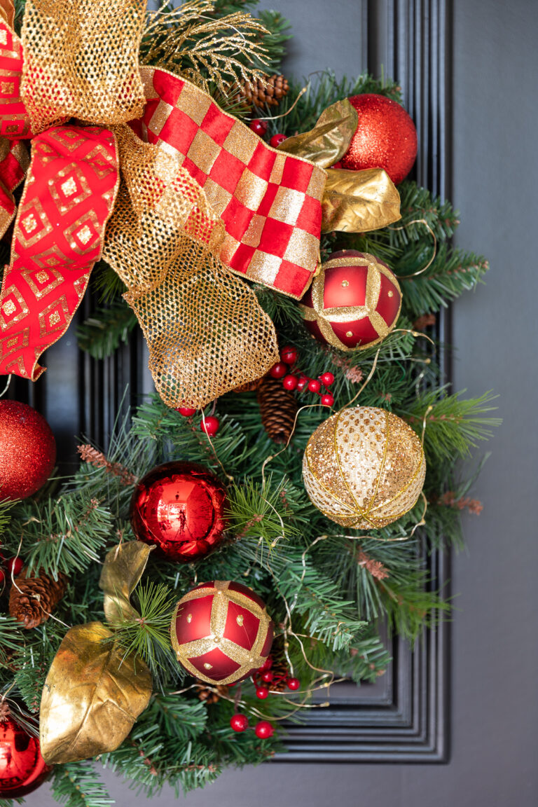 DIY Christmas wreath details, including checkered ribbon, gold ribbon, and red ribbon with a mix of red and gold ornaments and greenery.