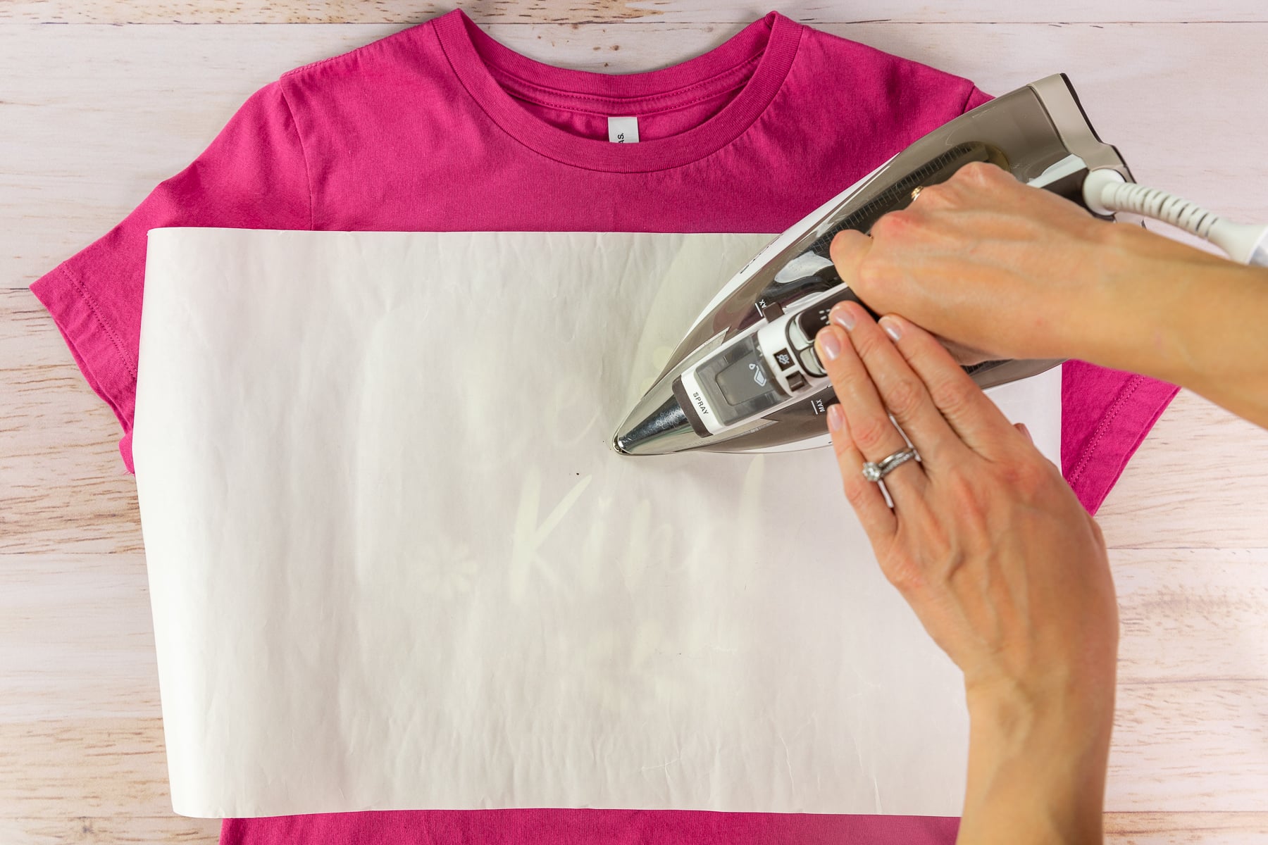 Pressing an HTV design onto a shirt with a household iron.