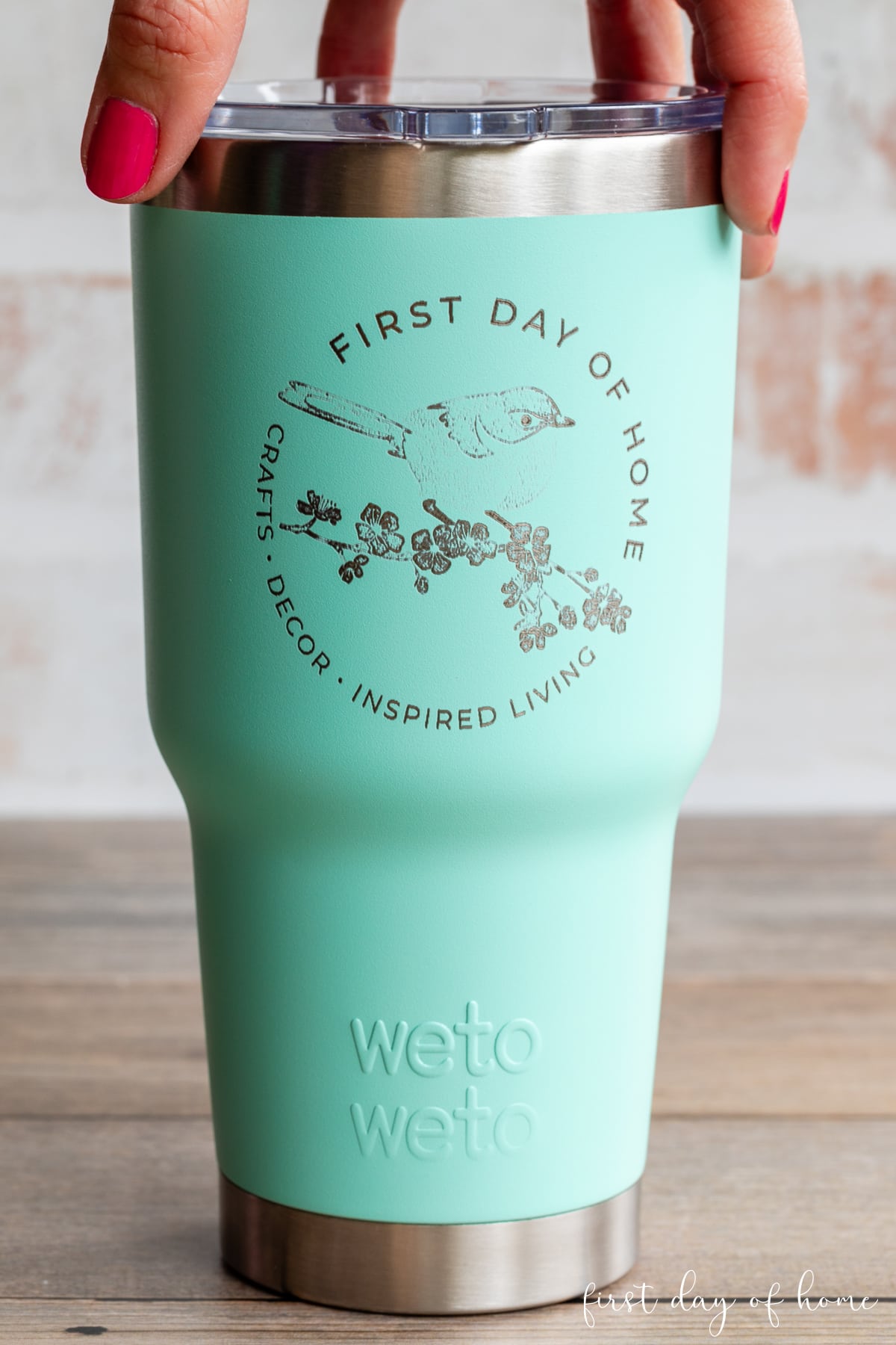 30 ounce tumbler engraved with a custom logo with a hand holding the lid from the top.